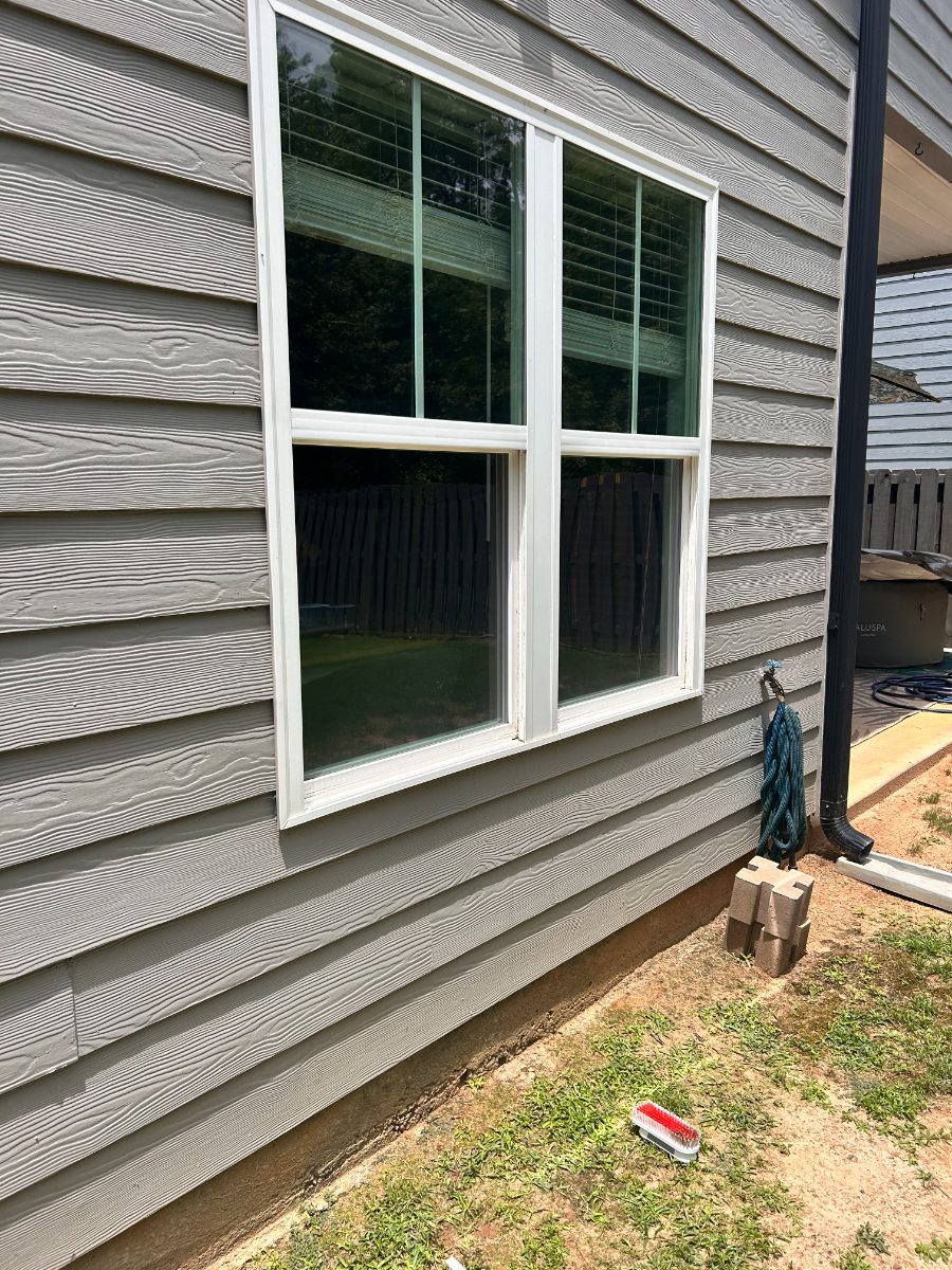 Same window after EXClean cleaning — double-hung on gray siding, exterior grime cleared