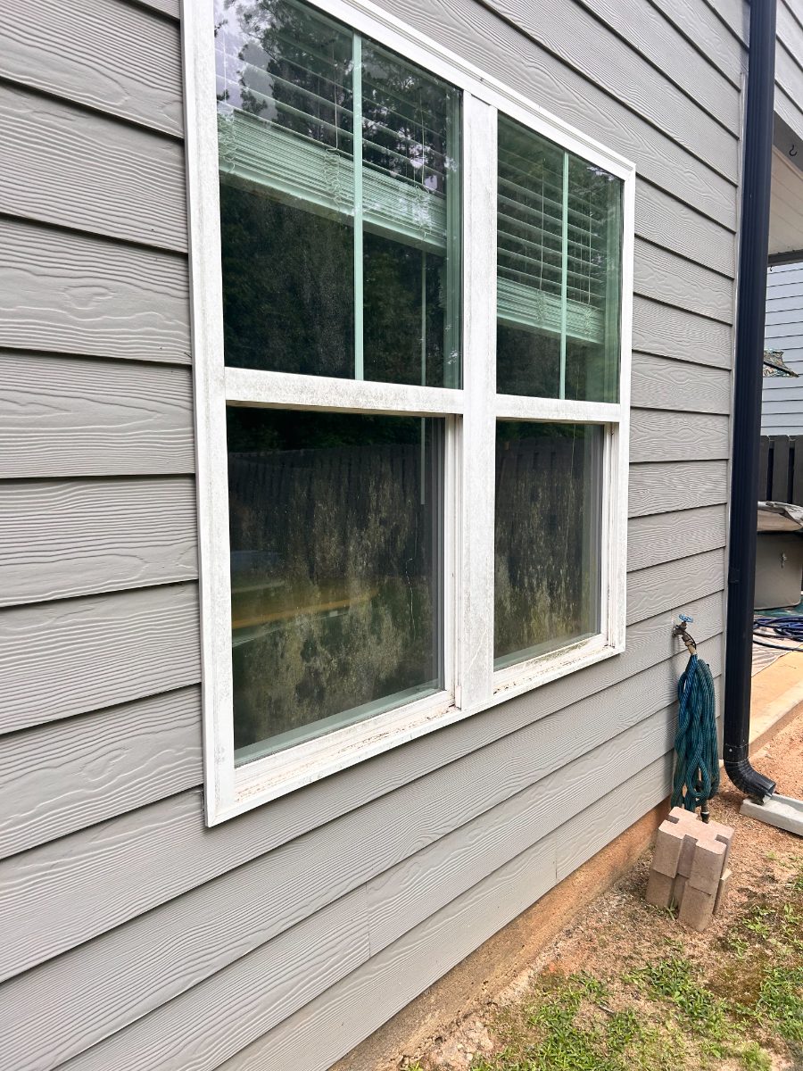 Dirty window before EXClean cleaning — double-hung on gray siding, exterior grime cleared